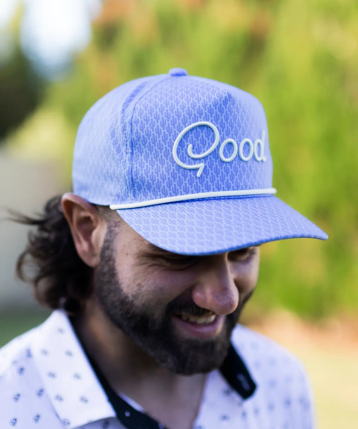 Man wearing a blue cap with 'Qood' logo outdoors