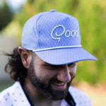 Man wearing a blue cap with 'Qood' logo outdoors
