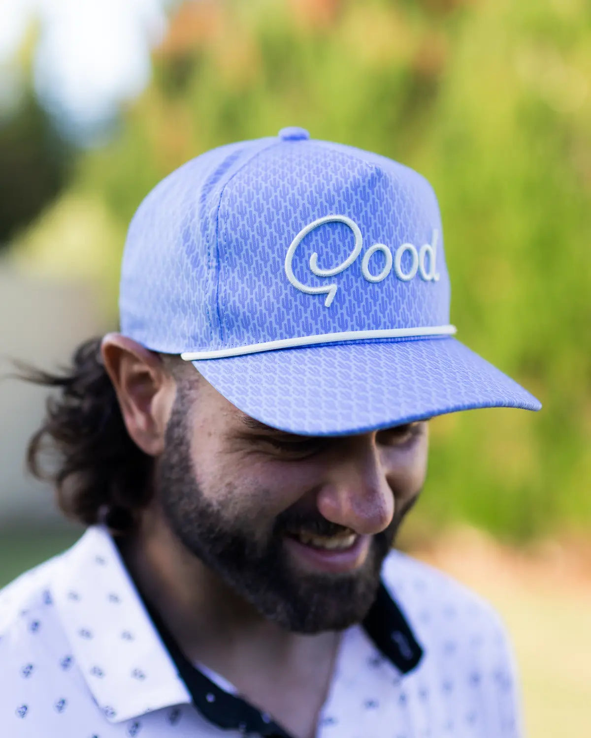 Man wearing a blue cap with 'Qood' logo outdoors