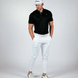 Man wearing a black polo shirt, white pants, and a white cap on a gray background