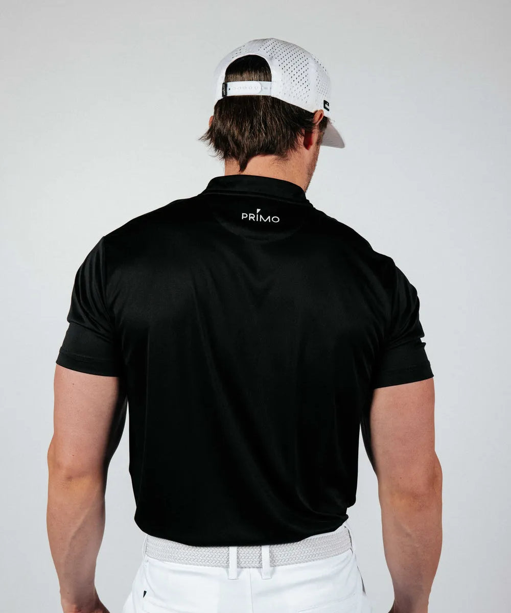 Man wearing a black Primo polo shirt and white cap on a plain background