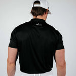 Man wearing a black Primo polo shirt and white cap on a plain background