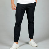 Person wearing black pants and white sneakers on a gray background