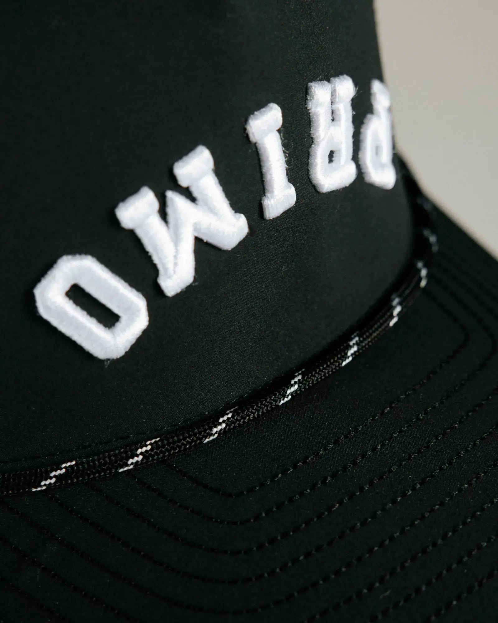Primo embroidered logo on front of cap, close up details