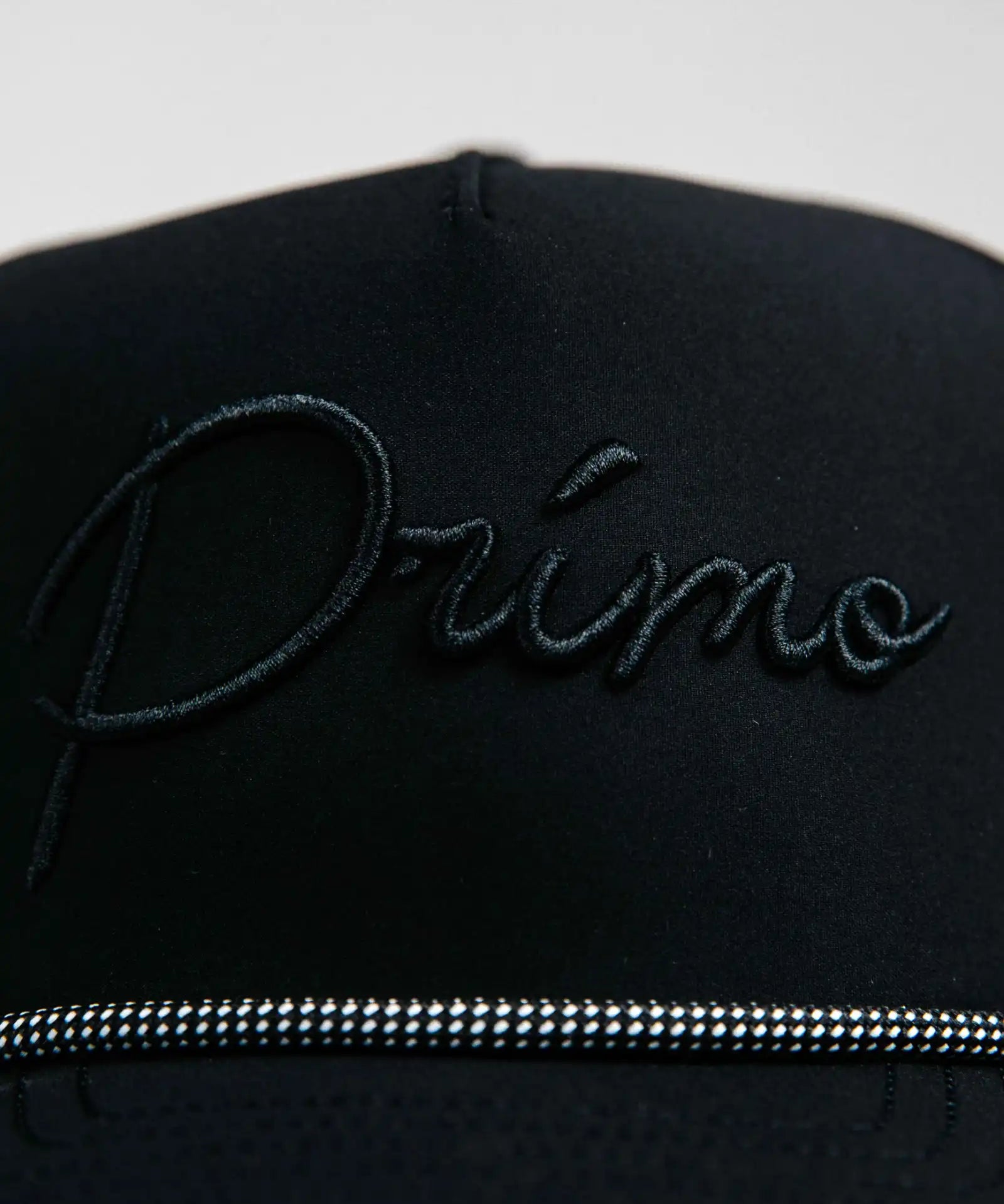 Black cap with 'Primo' embroidery on a light gray background