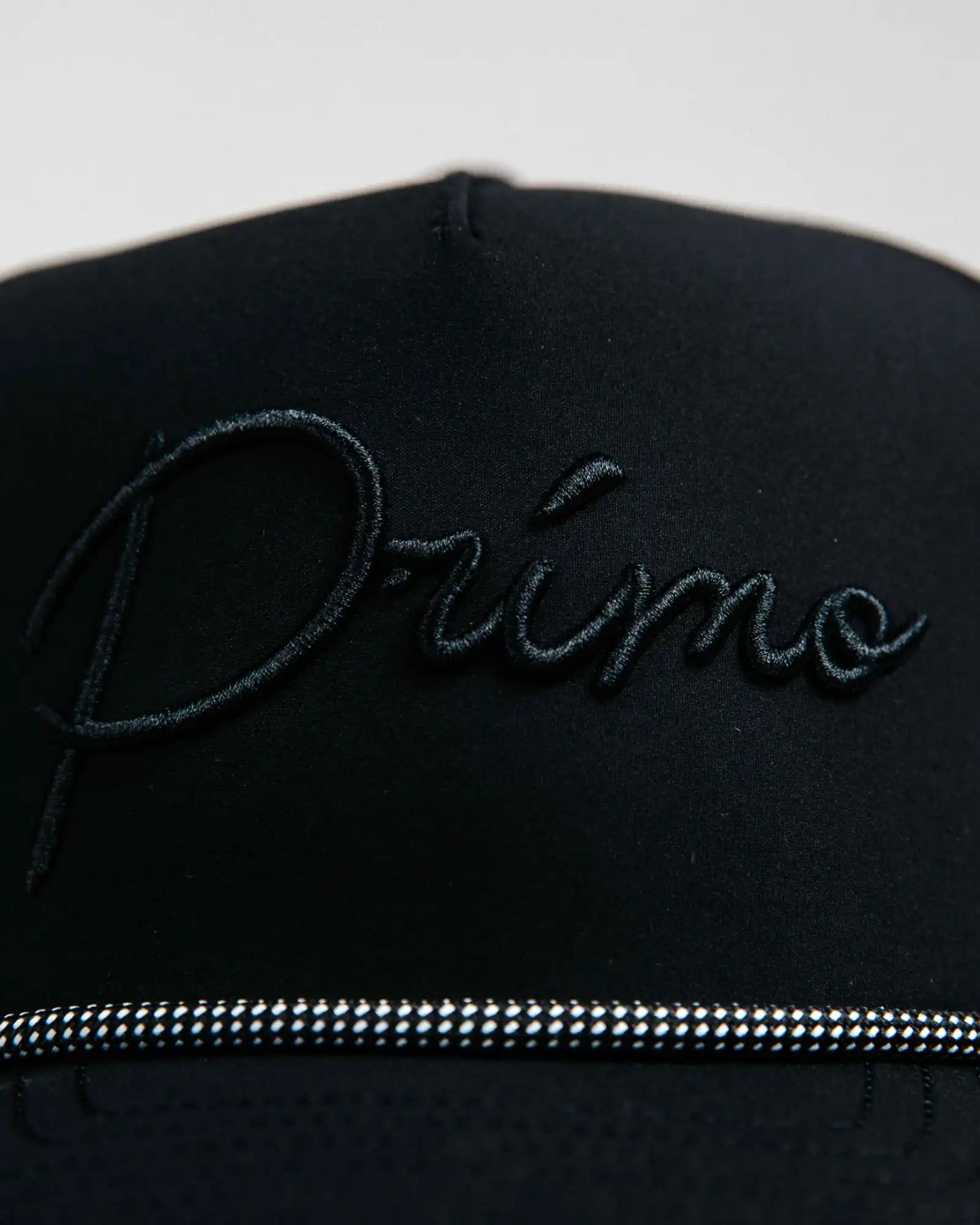 Black cap with 'Primo' embroidery on a light gray background