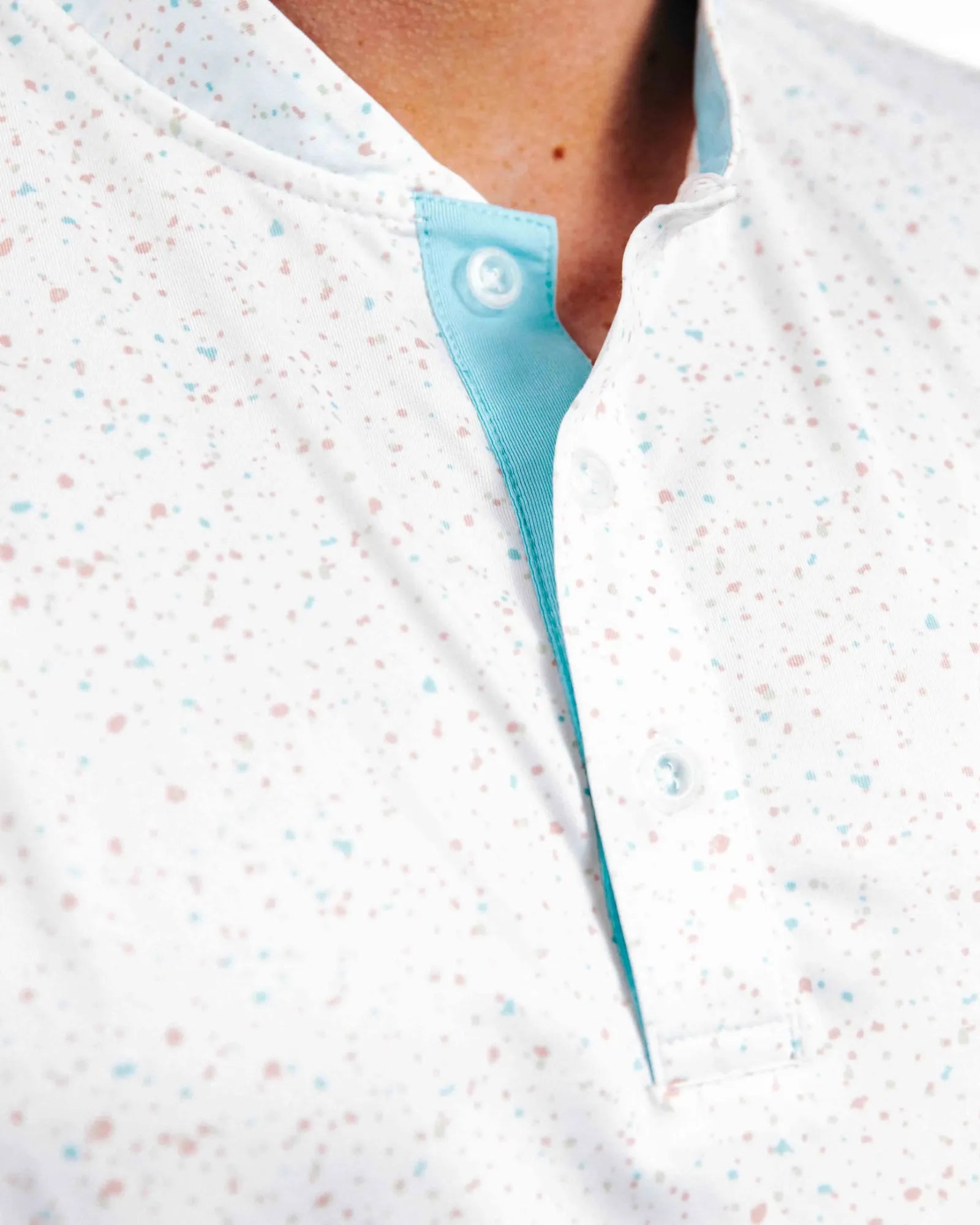 Close-up of a person wearing a light white and blue polo with front button placket on top