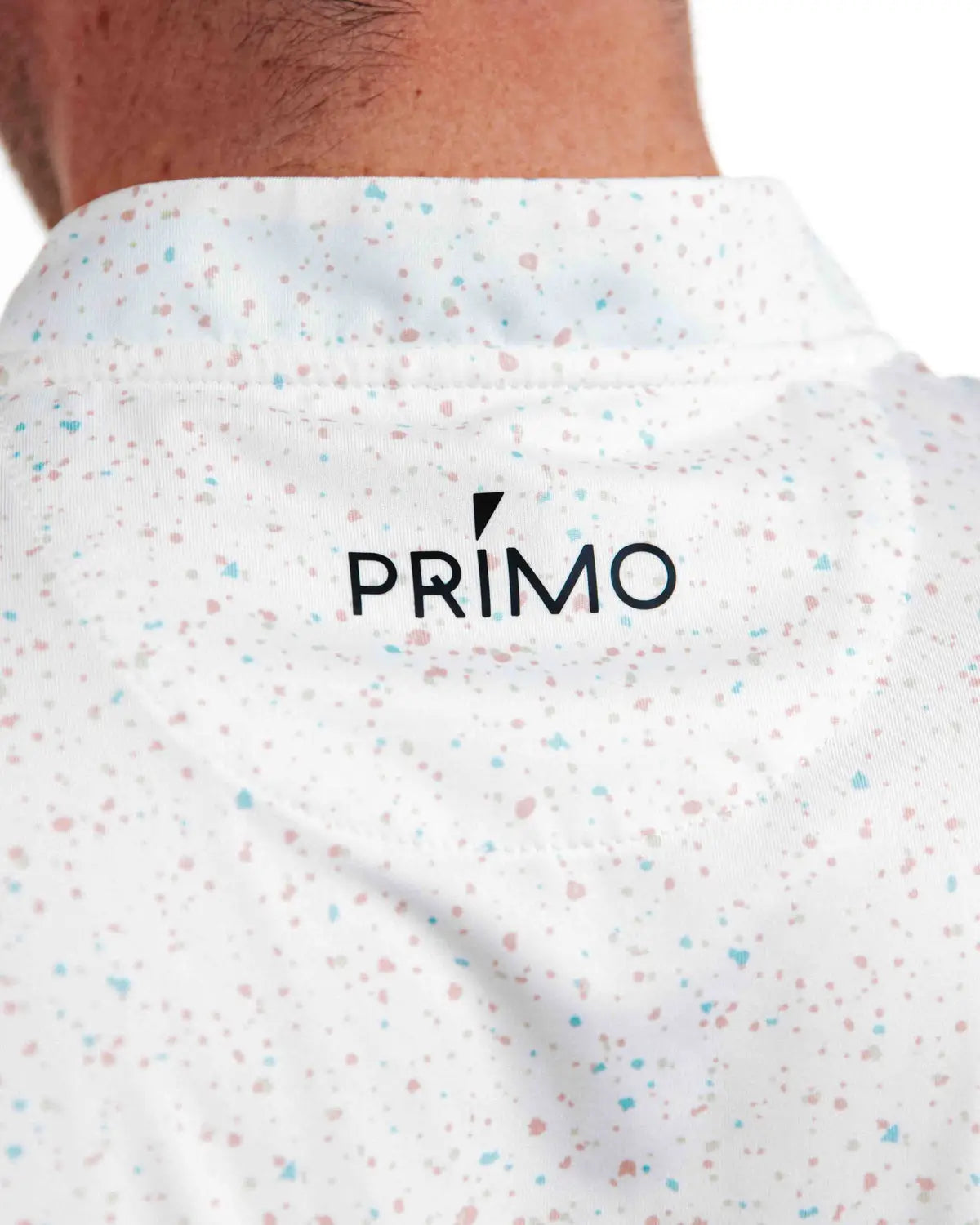 Close-up of a white shirt with colourful speckles and 'PRIMO' logo.