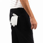 Person wearing black shorts with a white golf glove in the pocket on a white background