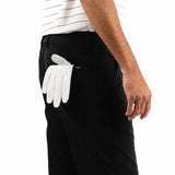 Person wearing black shorts with a white golf glove in the pocket on a white background