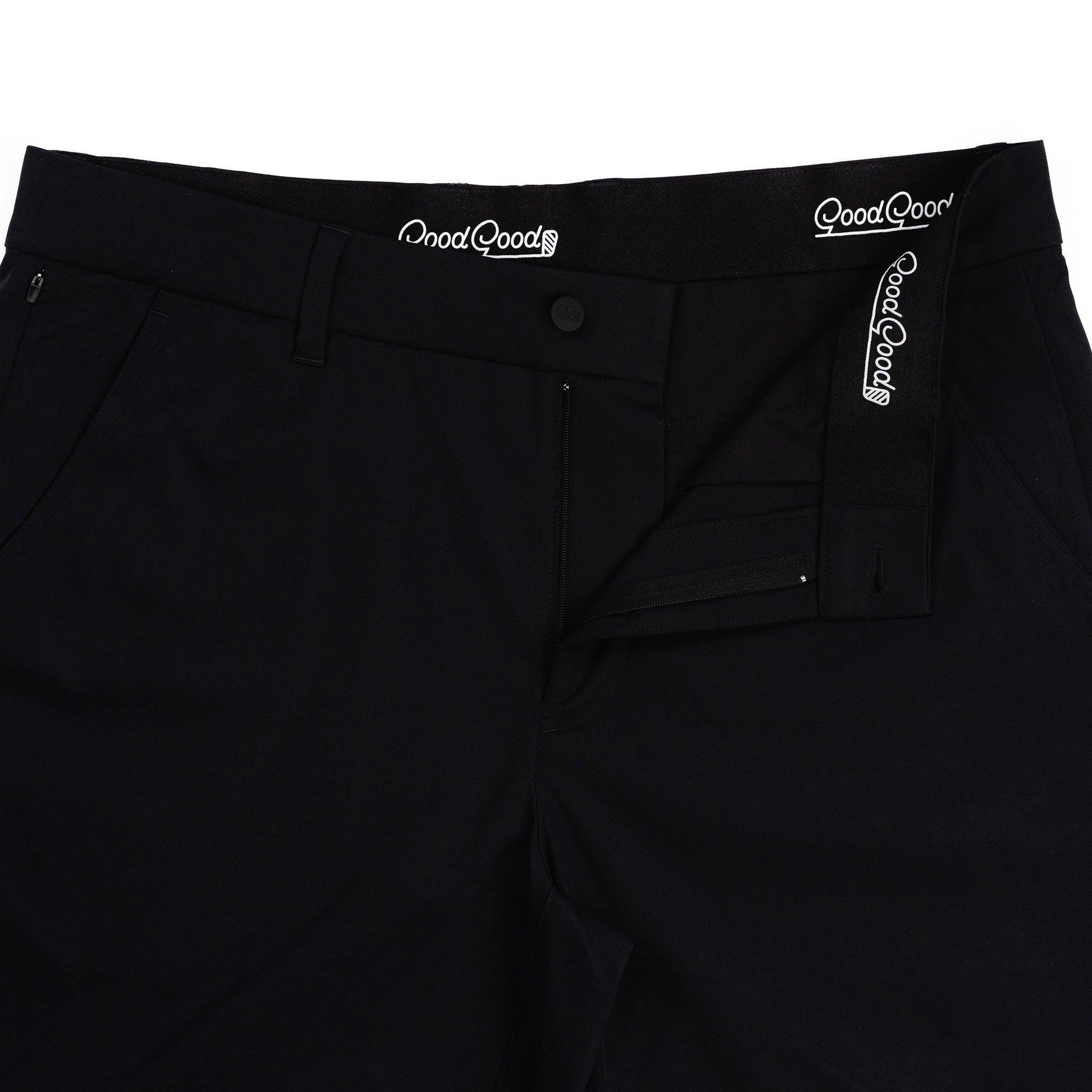 Close-up of black pants with 'Good Good' branding on waistband and pocket.