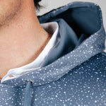 Close-up of a person wearing a blue speckled jacket with a white shirt underneath.