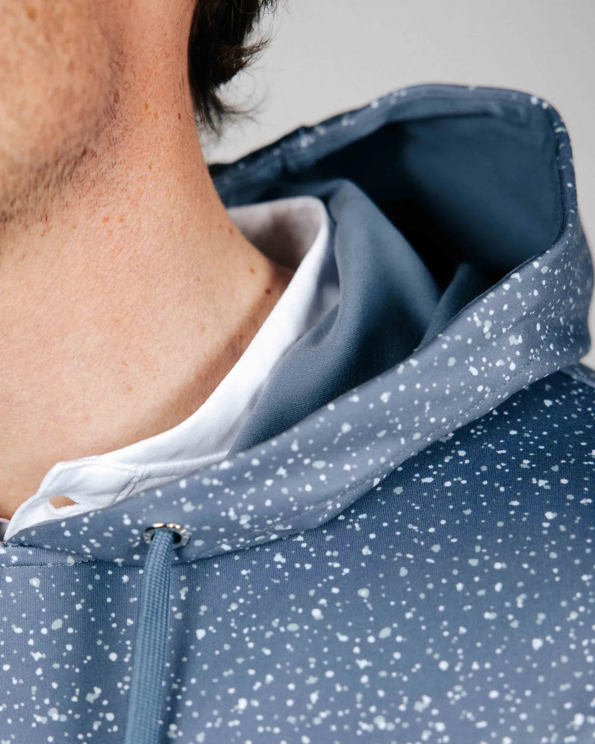Close-up of a person wearing a blue speckled jacket with a white shirt underneath.