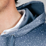 Close-up of a person wearing a blue speckled jacket with a white shirt underneath.