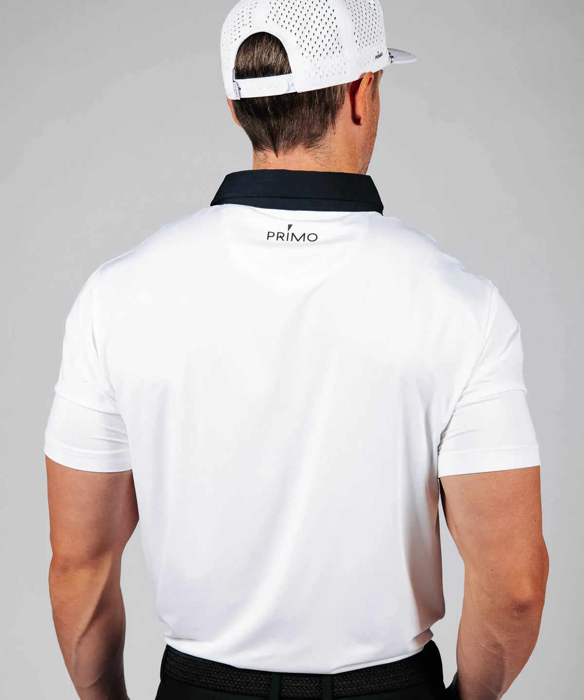 Man wearing a white polo shirt with 'Primo' logo on the back against a gray background