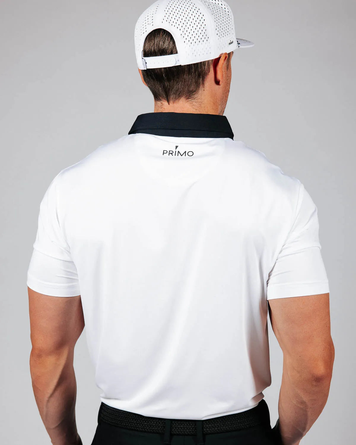 Man wearing a white polo shirt with 'Primo' logo on the back against a gray background