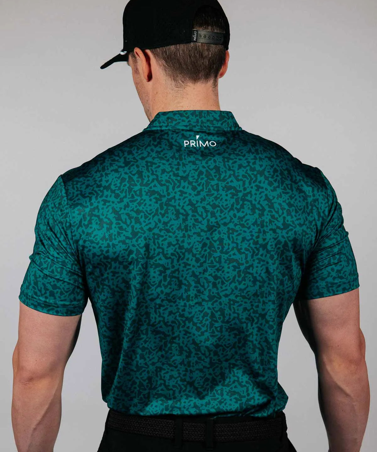 Man wearing a green patterned shirt with 'Primo' branding on the back, standing against a plain background.