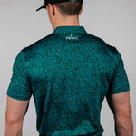 Man wearing a green patterned shirt with 'Primo' branding on the back, standing against a plain background.