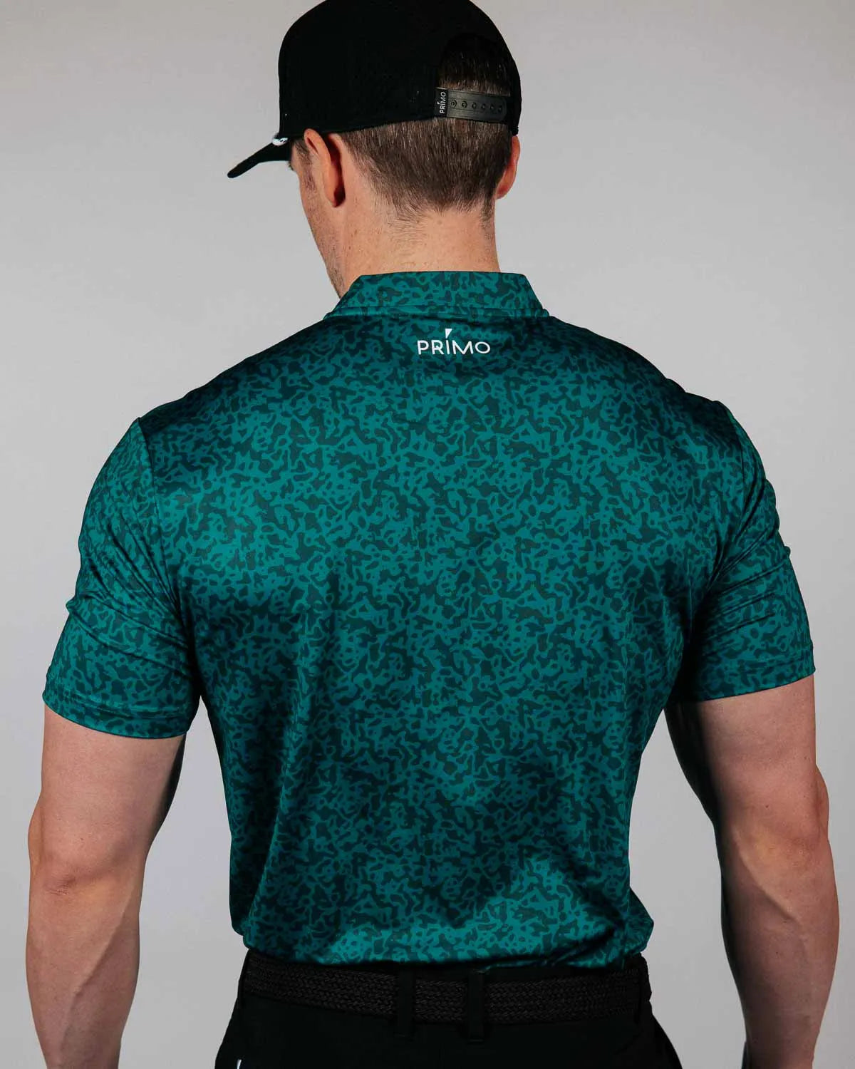 Man wearing a green patterned shirt with 'Primo' branding on the back, standing against a plain background.