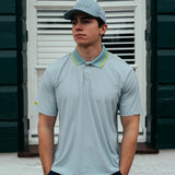 Man wearing a light blue polo shirt and cap standing in front of a white shutter.