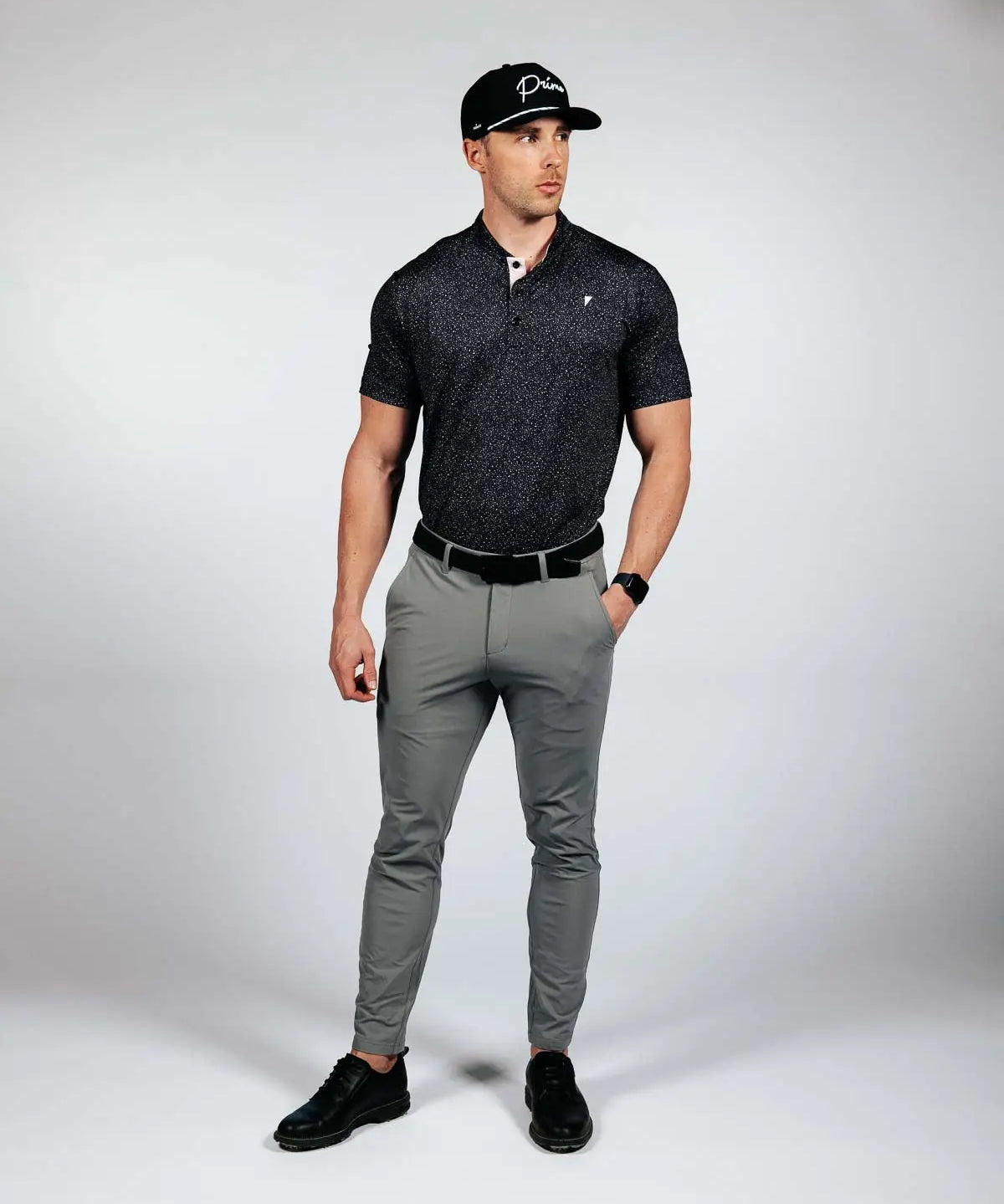 Man wearing a black polo shirt, gray pants, and black cap on a white background