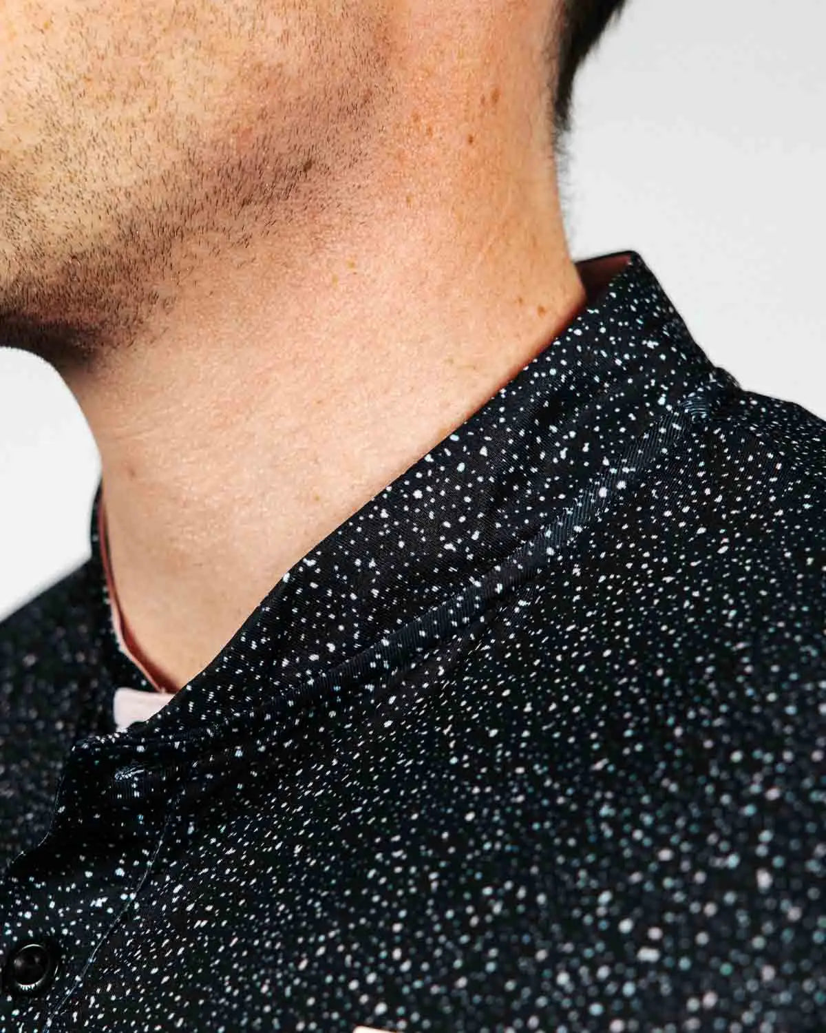 Close-up of a person wearing a black textured golf polo with a neutral background