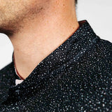 Close-up of a person wearing a black textured golf polo with a neutral background