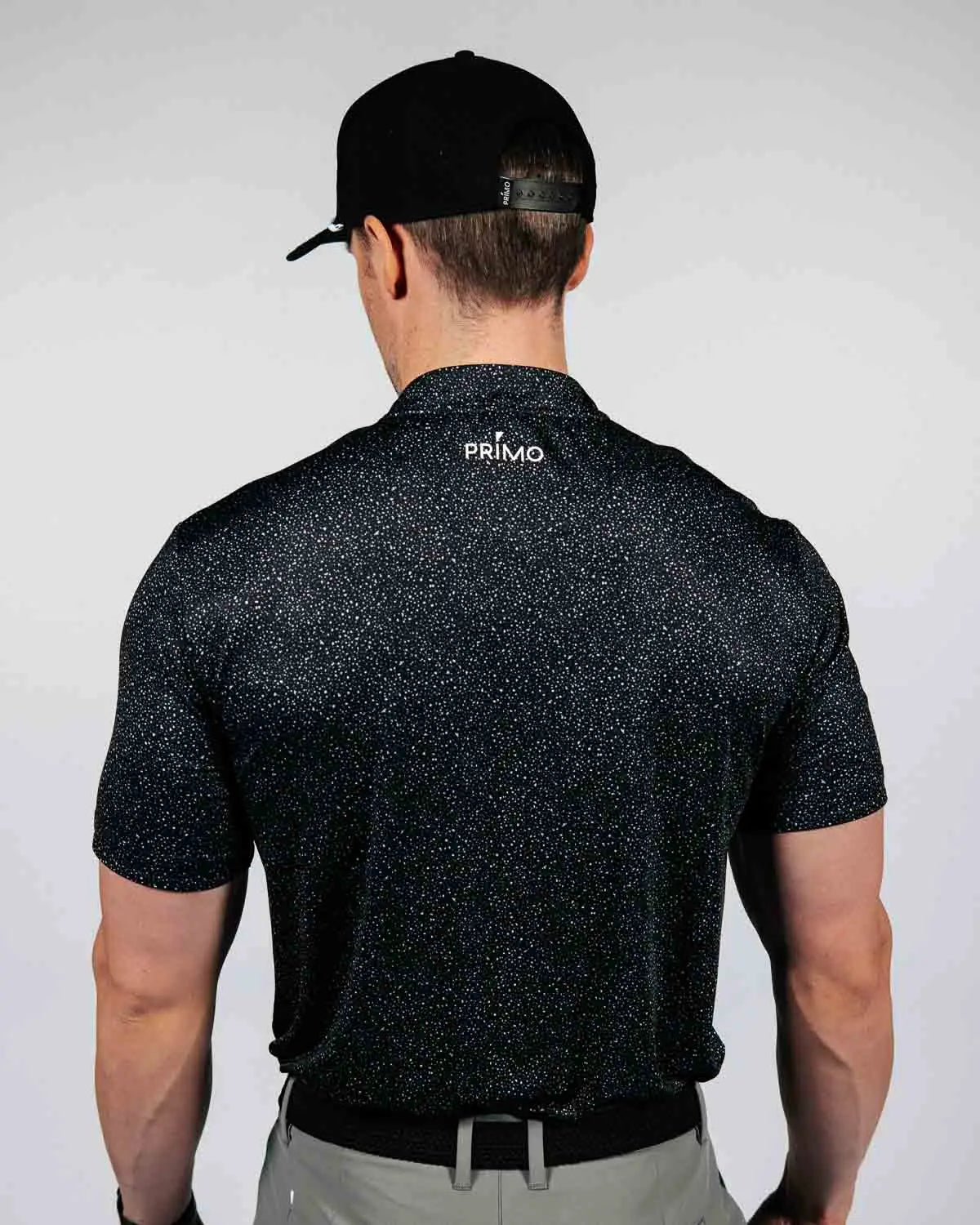 Man wearing a black speckled shirt with 'PRIMO' branding on the back, against a white background