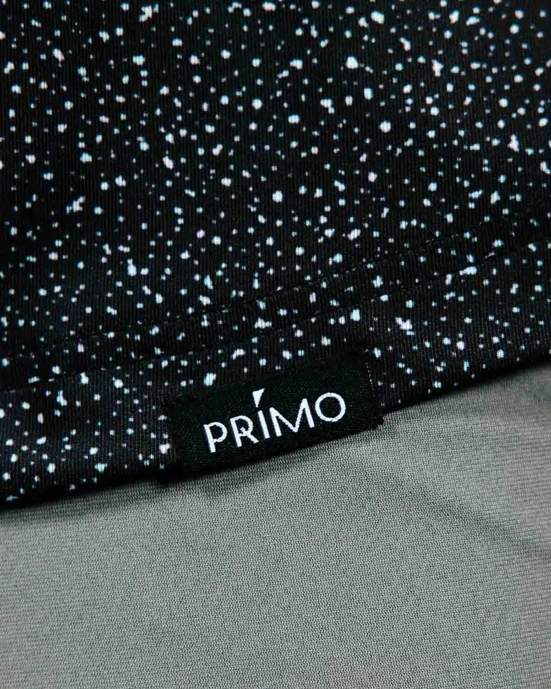 Close-up of a black polo with white speckles and a 'Primo' label.