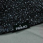 Close-up of a black polo with white speckles and a 'Primo' label.