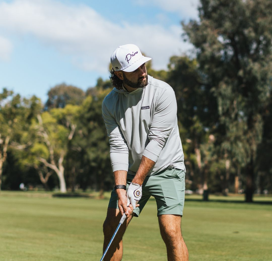 Man playing golf on a green course with trees in the background