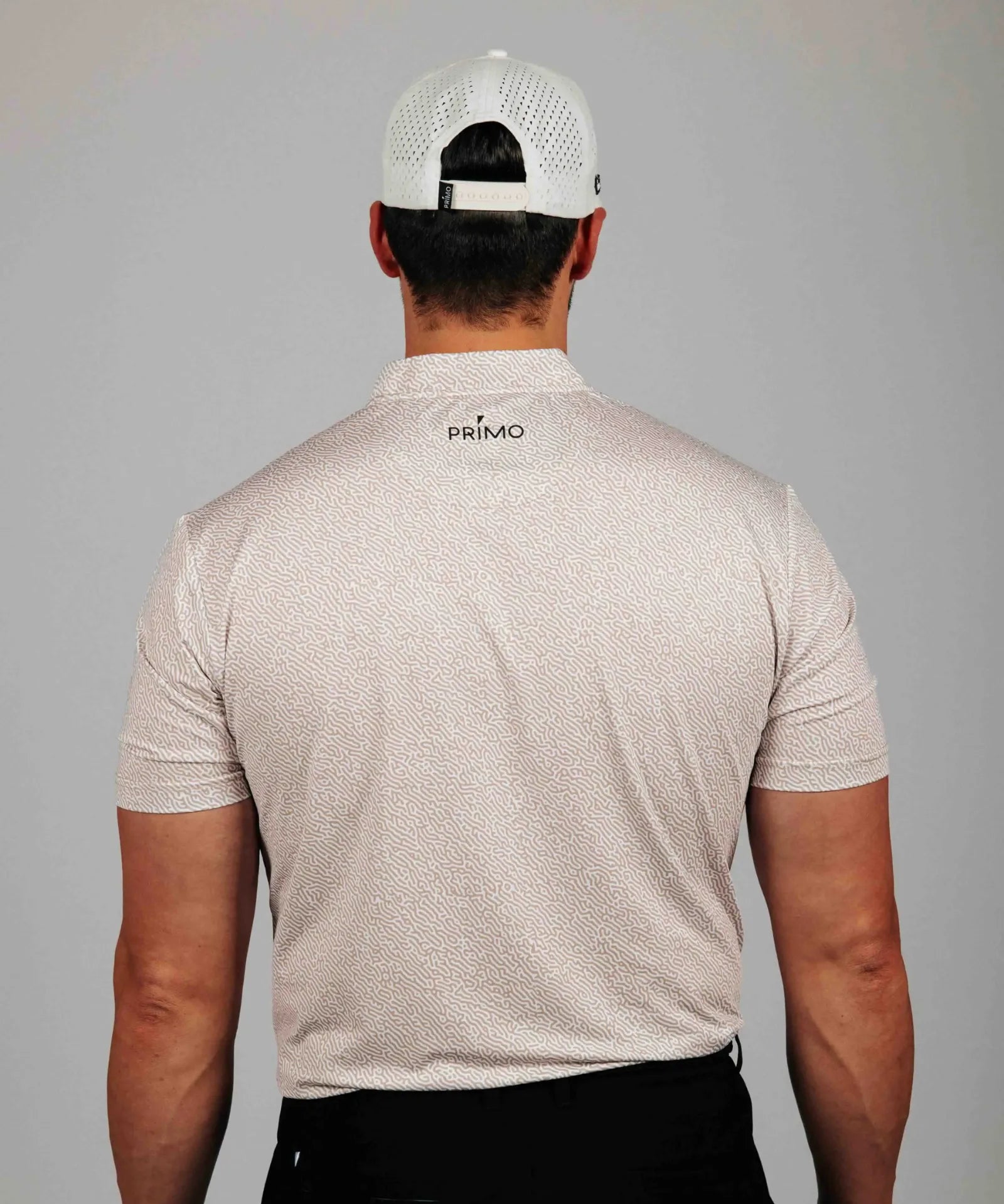 Man wearing a beige patterned shirt with 'Primo' branding on the back, against a gray background.