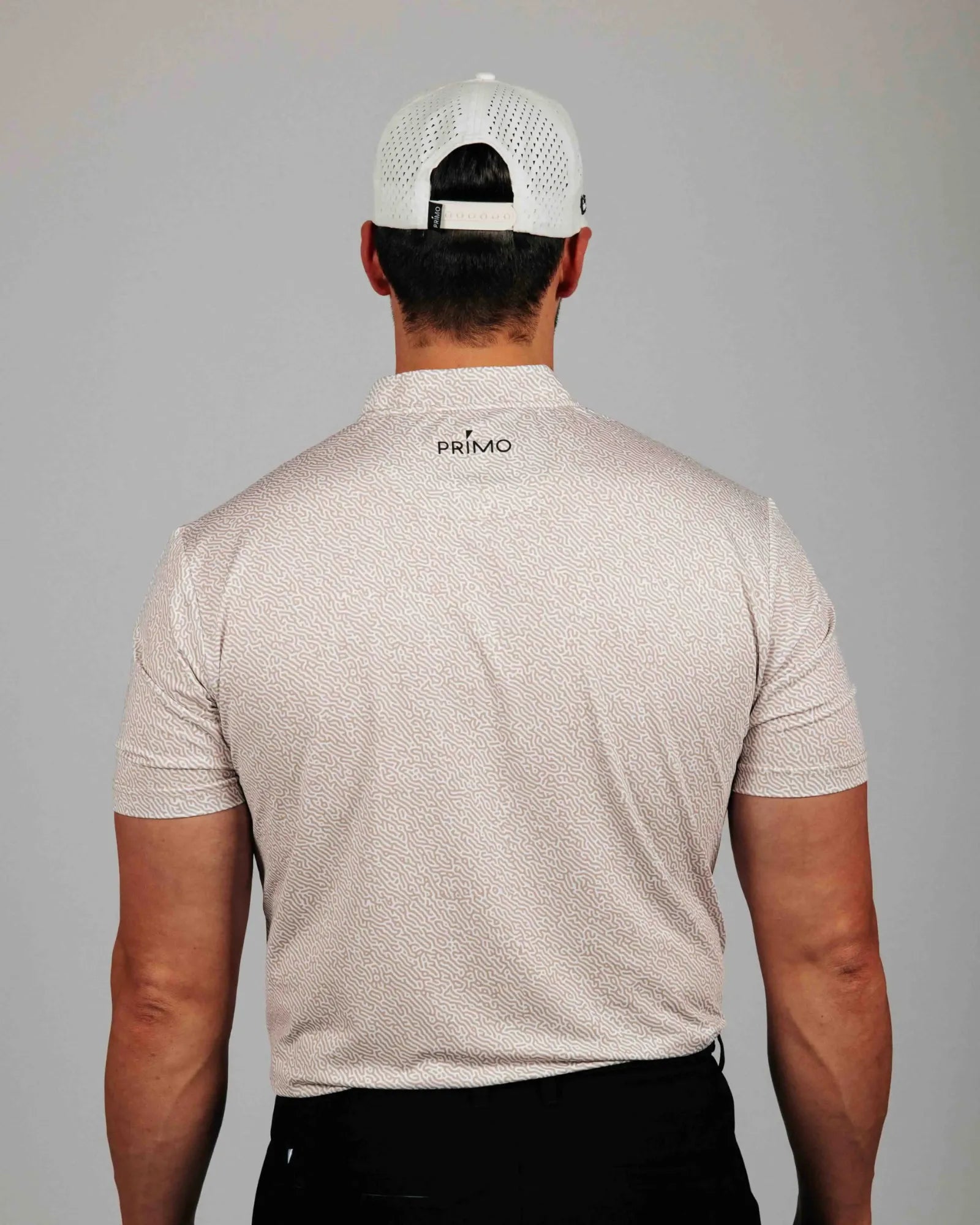 Man wearing a beige patterned shirt with 'Primo' branding on the back, against a gray background.