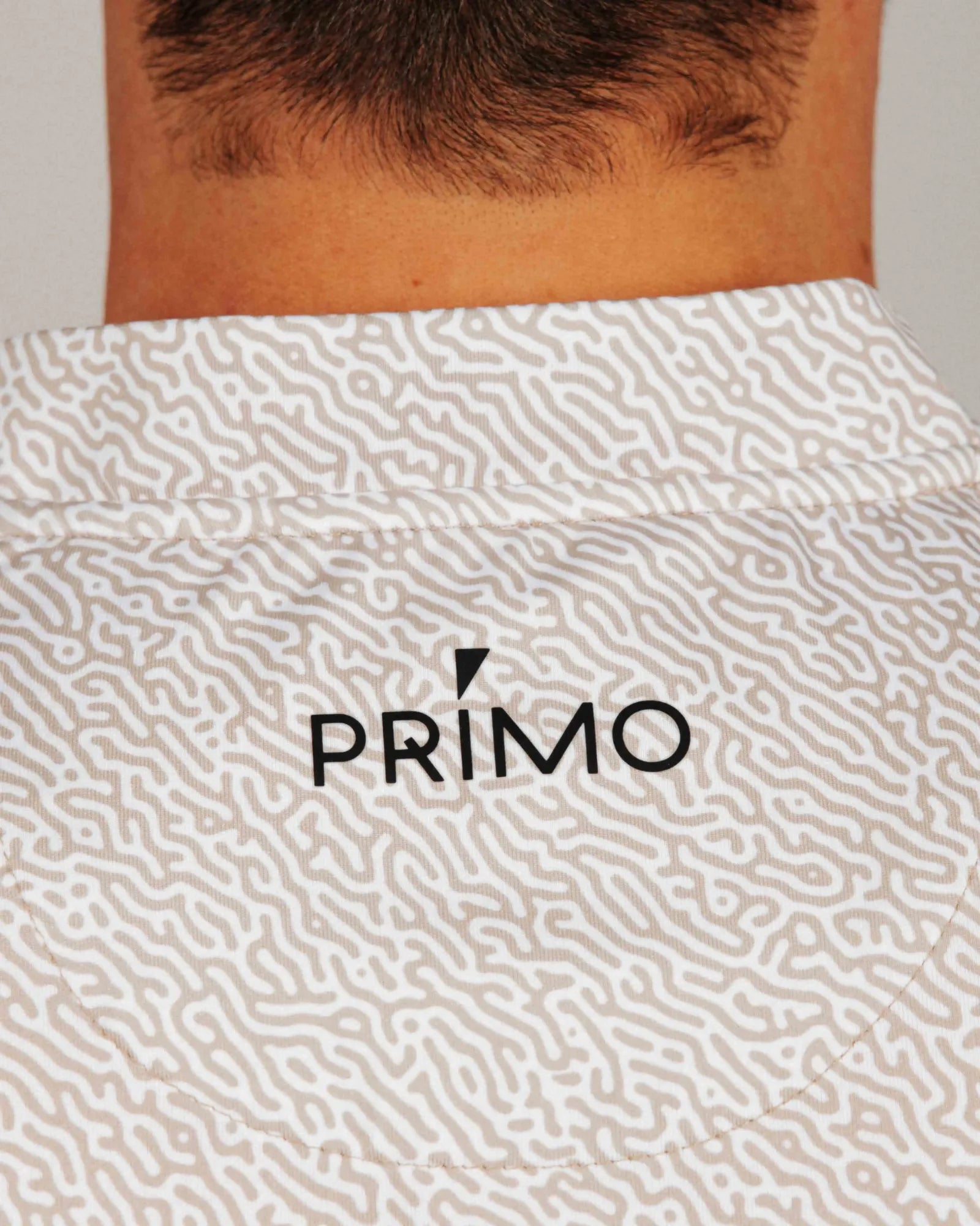 Sand coloured patterned shirt with 'PRIMO' logo on a neutral background