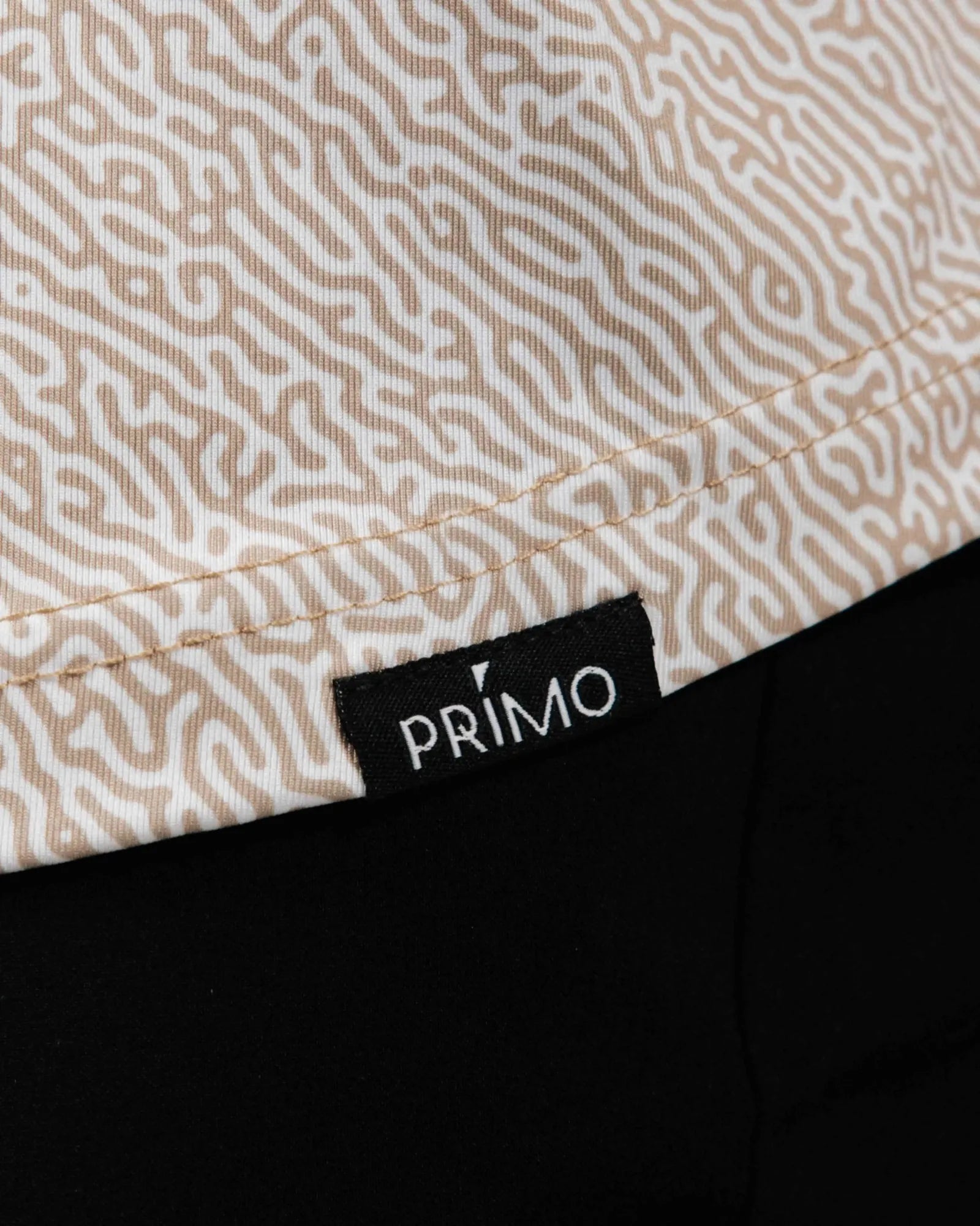 Close-up of a patterned fabric with a 'Primo' label on a black background