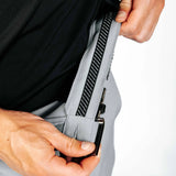 Person showing off interior details of grey pants. 