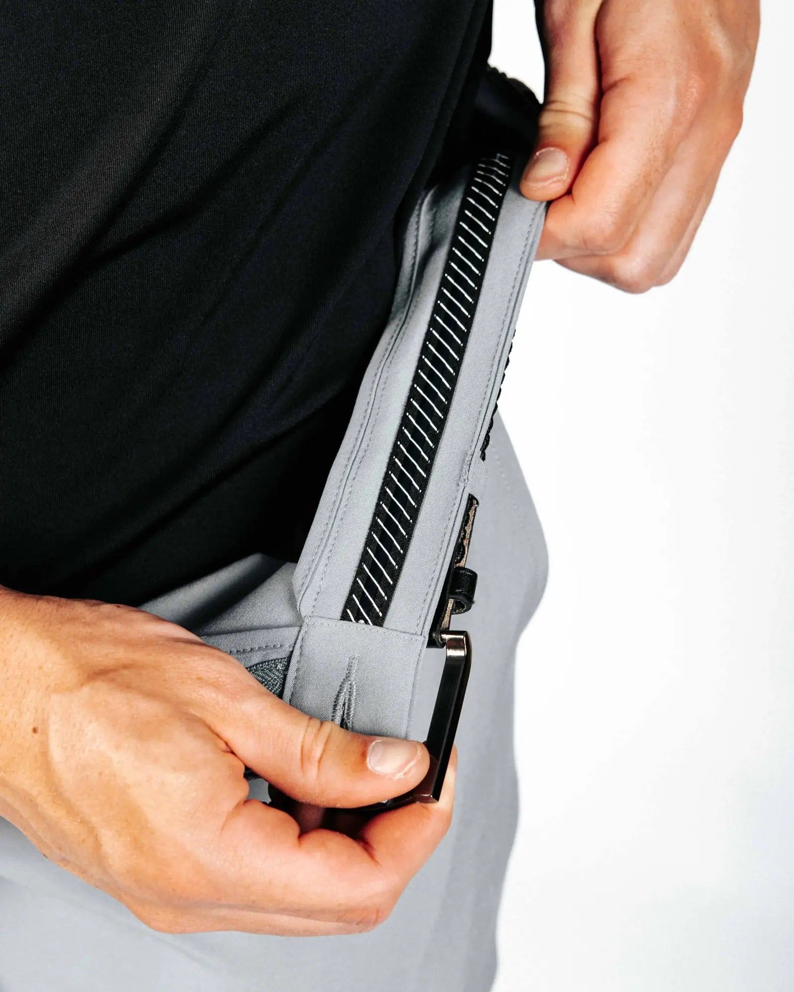 Person showing off interior details of grey pants. 