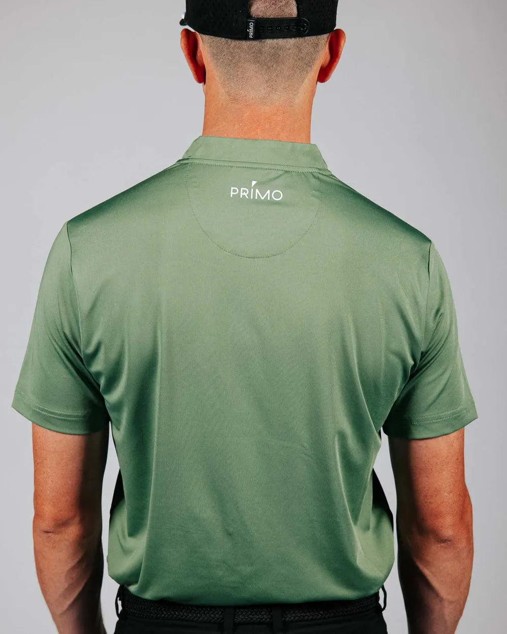 Person wearing a green 'Primo' polo shirt with a plain background