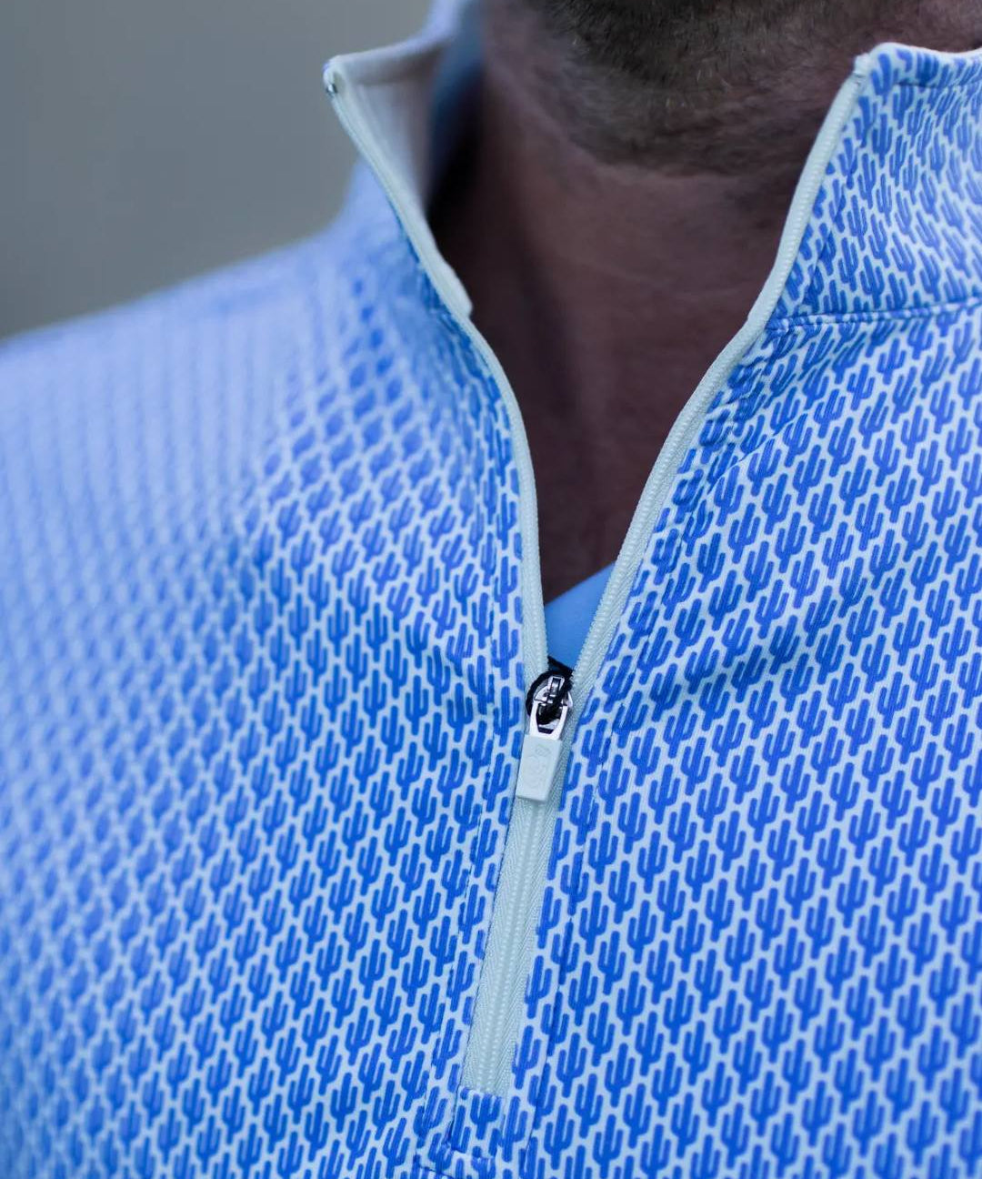 Close-up of a blue textured half-zip shirt with a blurred background