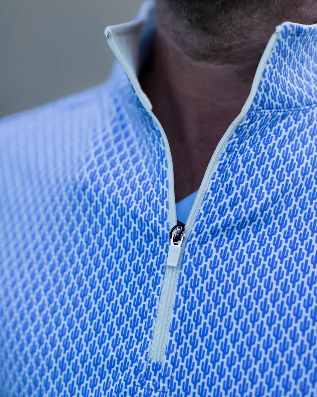 Close-up of a blue textured half-zip shirt with a blurred background