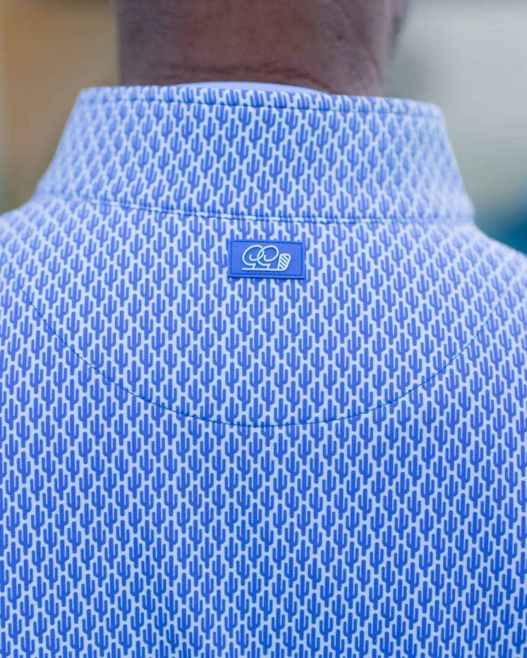Close-up of a blue textured shirt with a logo on the chest.
