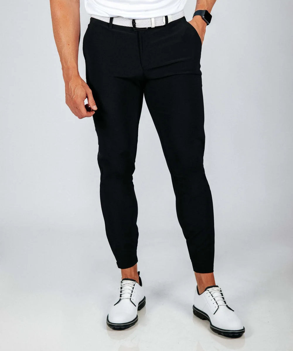 Person wearing black pants and white shoes on a plain background