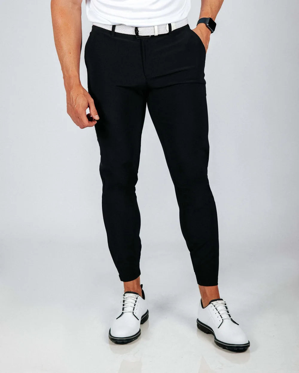 Person wearing black pants and white shoes on a plain background