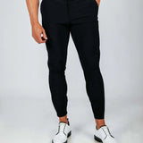 Person wearing black pants and white shoes on a plain background