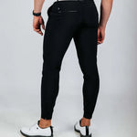 Person wearing black pants and white shoes on a light gray background