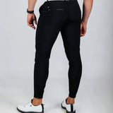 Person wearing black pants and white shoes on a light gray background