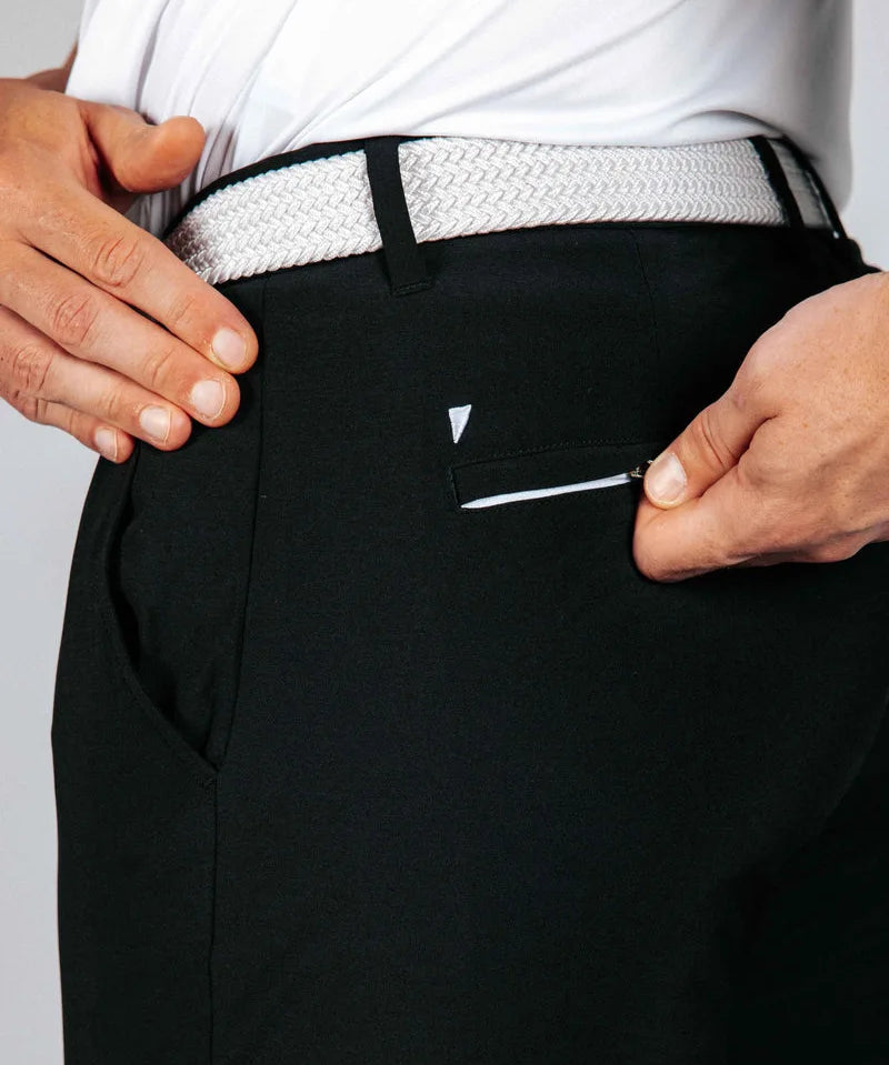 Person wearing black pants with a white belt and visible brand logo and back pocket zipper.