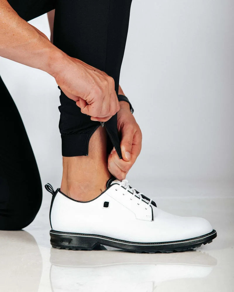 Person wearing a white shoe with black sole on a light gray background
