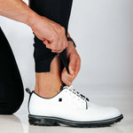 Person wearing a white shoe with black sole on a light gray background
