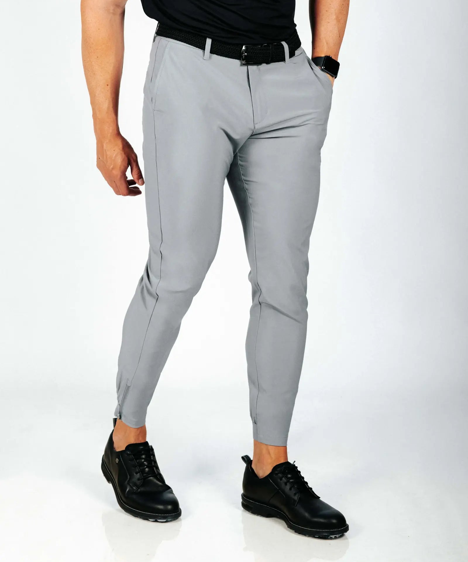 Person wearing gray pants and black shoes on a white background
